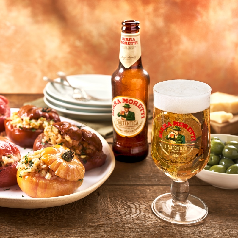 Birra Moretti and stuffed peppers arranged on a table.